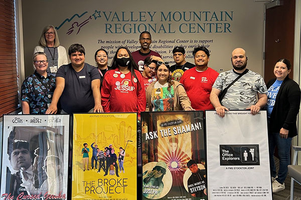 A group of people stands indoors in front of a 